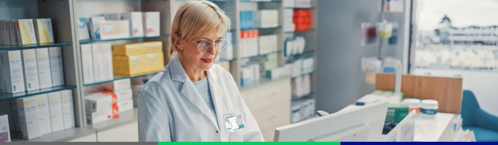 Strefa Farmaceuty Farmaceuta stoi przed ladą z komputerem