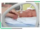 wcześniak w inkubatorze trzymany za rączkę przez opiekuna