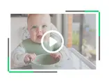 Niemowlę siedzące na krzesełku do karmienia z miseczką przed nim