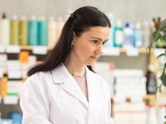 Kobieta w białym fartuchu laboratoryjnym korzysta z komputera