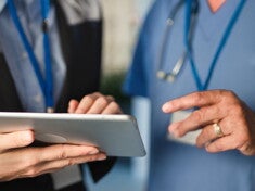 Doktor i pielęgniarka wspólnie przeglądają informacje na tablecie w placówce medycznej