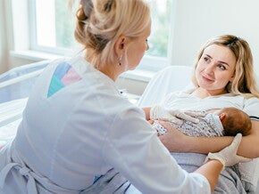 dziecko na rękach mamy oraz lekarz badający dziecko