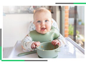 Niemowlę siedzące na krzesełku do karmienia z miseczką przed nim