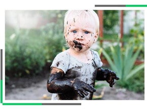 Dziecko ubrudzone błotem siedzące w ogrodzie