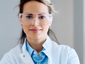 Naukowczyni w okularach ochronnych stoi w nowoczesnym laboratorium medycznym