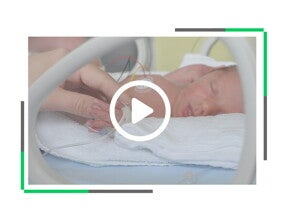wcześniak w inkubatorze trzymany za rączkę przez opiekuna