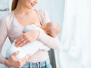 Młoda mama karmiąca piersią niemowlę w domu