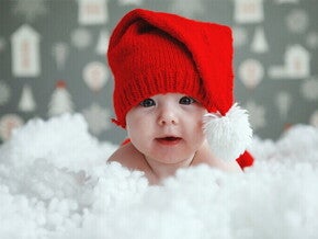 dziecko w czerwonej czapeczce leżące w chmurze śniegu