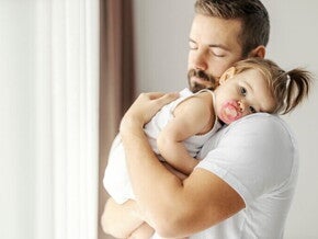 smutna dziewczynka jest trzymana na rękach przez tatę