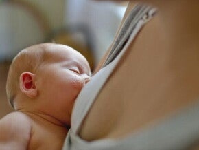 dziecko karmione piersią na rękach mamy z wysypką na policzku