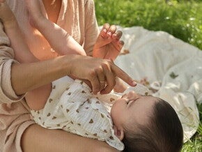 Opiekunka czule dotyka noska małego dziecka, trzymając go na kolanach