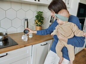 Mama trzymająca dziecko na rękach i przygotowująca mleko modyfikowane