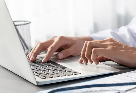 lekarz pracujący na laptopie, robiący notatki