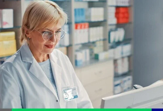 Farmaceuta stoi przed ladą z komputerem