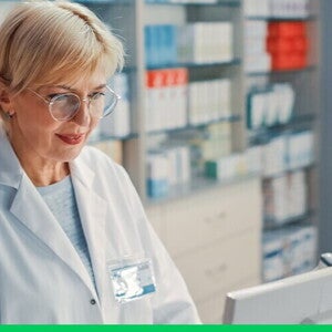 Farmaceuta stoi przed ladą z komputerem