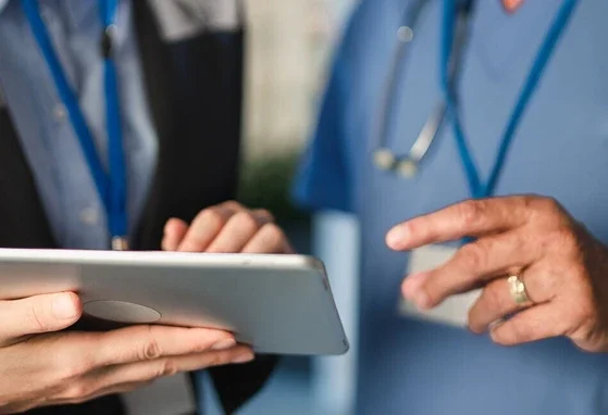 Doktor i pielęgniarka wspólnie przeglądają informacje na tablecie w placówce medycznej