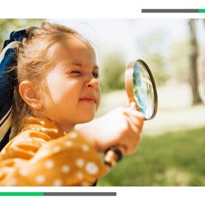 Mała dziewczynka patrzy przez szkło powiększające