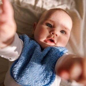 Niemowlę sięga w górę, wyciągając rączki w stronę nieba