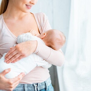 Młoda mama karmiąca piersią niemowlę w domu