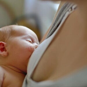 dziecko karmione piersią na rękach mamy z wysypką na policzku