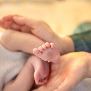 Małe nóżki dziecka w dłoniach mamy