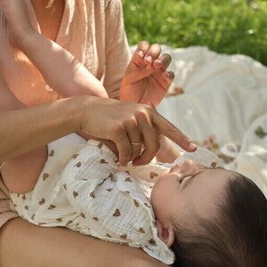 Opiekunka czule dotyka noska małego dziecka, trzymając go na kolanach