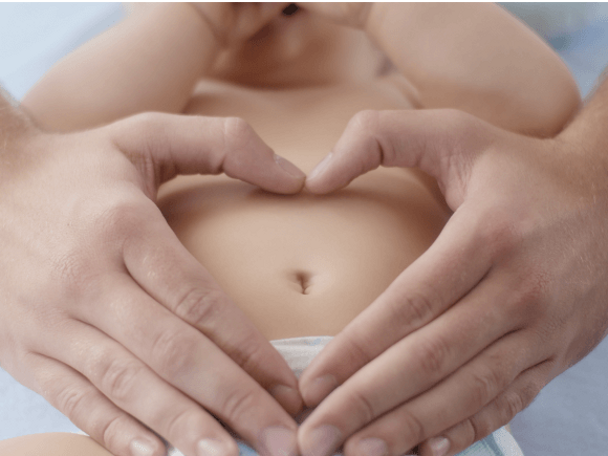 Tata trzyma ręce na brzuchu dziecka