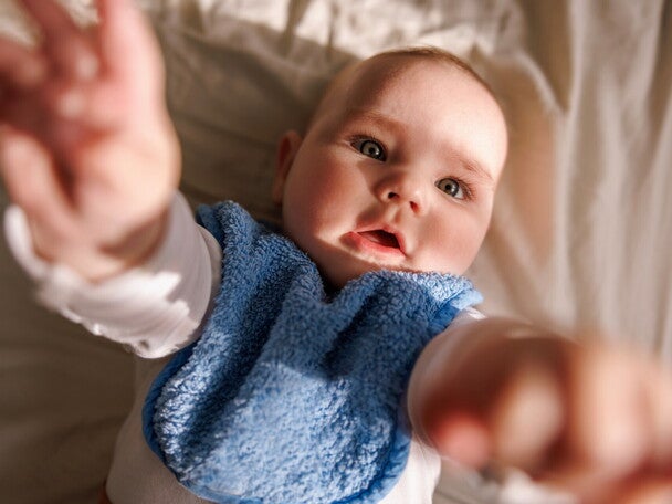 Niemowlę sięga w górę, wyciągając rączki