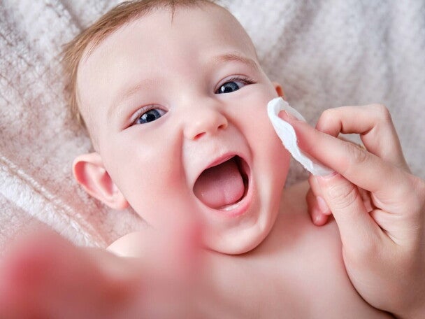 Radosne niemowlę podczas delikatnej pielęgnacji skóry