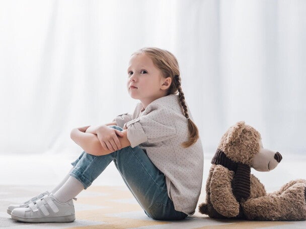 Smutna dziewczynka siedzi z misiem