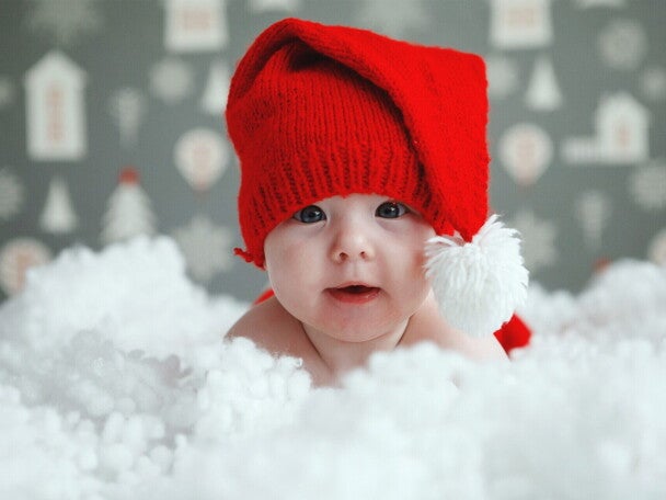 dziecko w czerwonej czapeczce leżące w chmurze śniegu