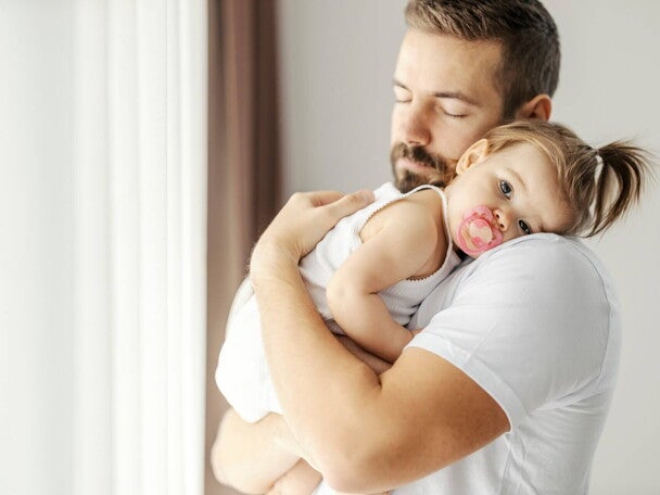 Smutna dziewczynka jest trzymana na rękach przez tatę