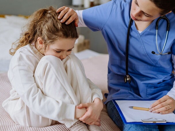 Lekarz siedzi obok małej pacjentki i ją pociesza