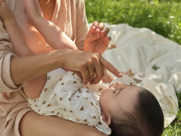 Opiekunka czule dotyka noska małego dziecka, trzymając go na kolanach