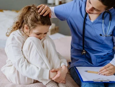 Lekarz siedzi obok małej pacjentki i ją pociesza