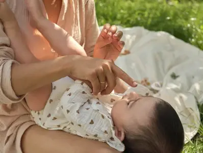 Opiekunka czule dotyka noska małego dziecka Opiekunka czule dotyka noska małego dziecka, trzymając go na kolanach